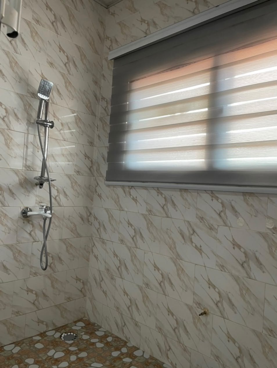 Bathroom with a shower and marble-style tiles