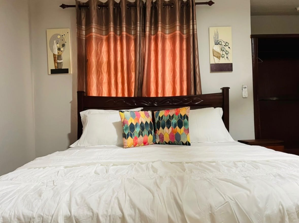 Bedroom with a large bed, white linen and colourful cushions